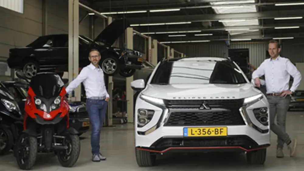 Arie en Thijs bij ingang werkplaats met Qooder en Mitsubishi Eclipse Cross PHEV